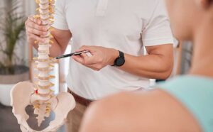 A person seated at a desk adjusting their sitting position to maintain upright posture.