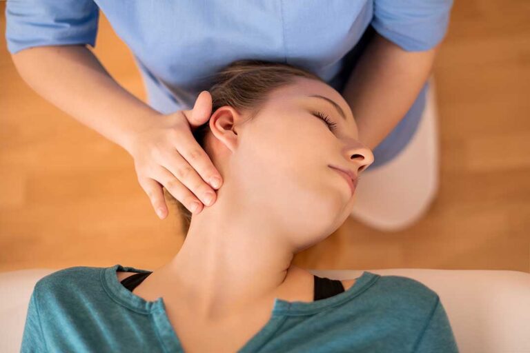 A clinician discusses back pain with an adult seated beside an examination table.