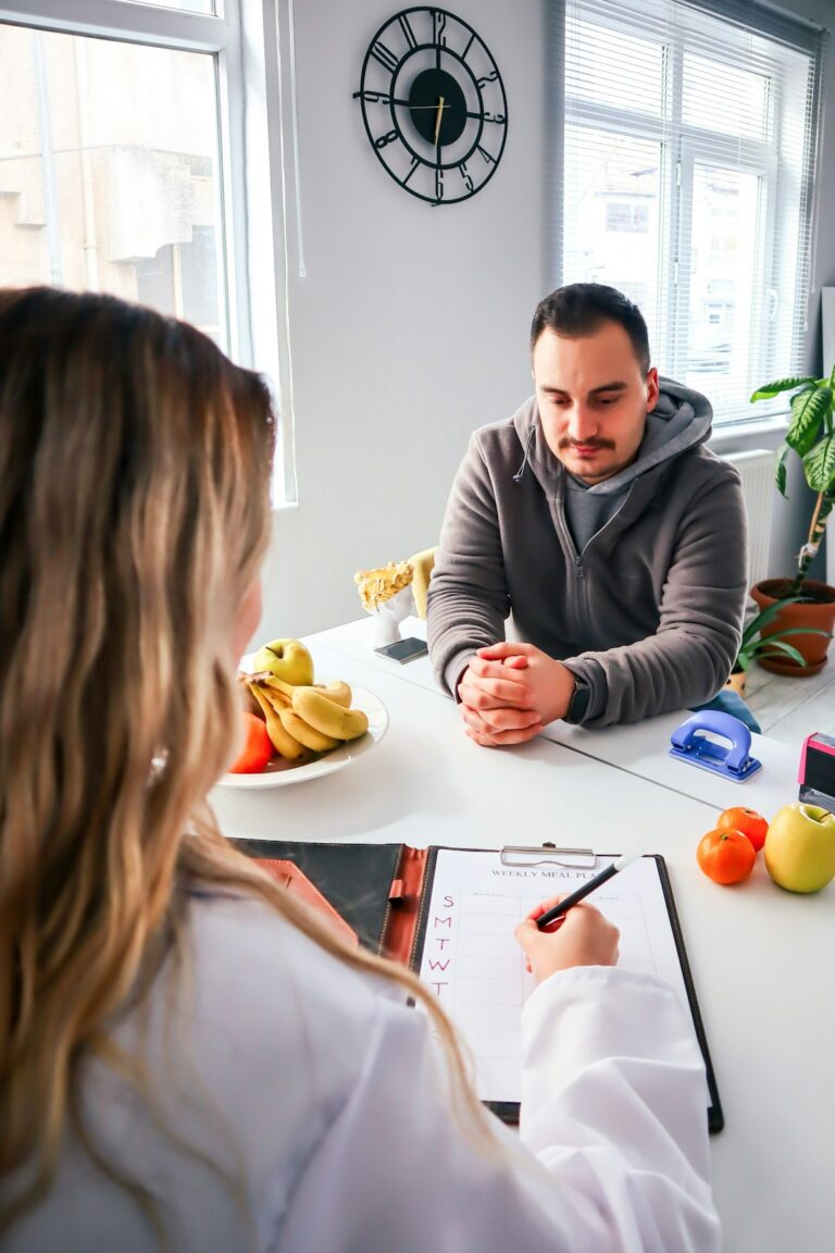Person writing digestive symptoms in a journal beside water and a balanced high-fiber meal.